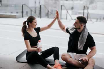 Wall Mural - young happy couple handsome brunette man and beautiful woman in sportswear sitting on yoga mat, give each other high five , street workout, healthy fit lifestyle