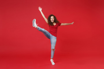 Wall Mural - Full length portrait of excited young african american girl in casual t-shirt isolated on red background studio portrait. People lifestyle concept. Mock up copy space. Rising spreading hands and legs.