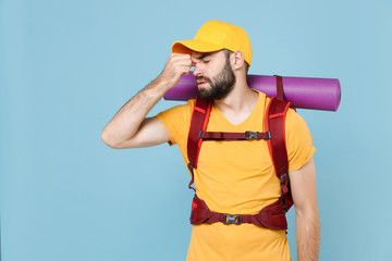 Wall Mural - Tired traveler young man in yellow t-shirt cap with backpack isolated on blue background. Tourist traveling on weekend getaway. Tourism discovering hiking concept. Keep eyes closed, put hand on nose.