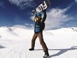 Snowboardzista triumfujący z deską ponad głową na stoku we francuskich Alpach 