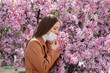 © Andrii - A young girl takes off her mask and breathes deeply after the end of the pandemic on a Sunny spring day, in front of blooming gardens. Protection and prevention covid 19