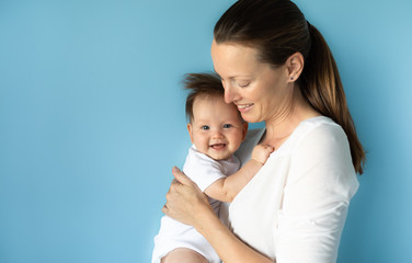 Portrait of mother holding happy little baby girl. In studio shot. 