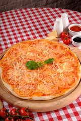 Neapolitan pizza with parmesan cheese, slices of tomato, fresh basil and tomatoes sauce, served on a wooden board for a dinner in italian restaurant background, top view. Classic Italy food.