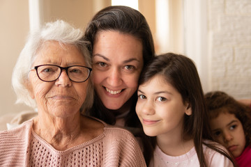 Portrait of female multigenerational family spending time together Indoors at home living room. Affectionate, bonding, love, generation concept.