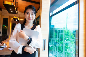 Portrait of young asian businesswoman holding Tablet and pen while standing at meeting room, smiling, copy space.