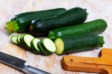 Wall Mural - Close-up of fresh green zucchini cut on wooden desk in kitchen