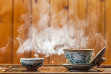 Cup of chinese tea with cloud of steam on wooden background