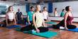 © JackF - Group of young positive people doing yoga in dance hall. Focus on brunet man