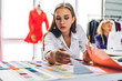 © Art_Photo - Portrait of young beautiful pretty woman fashion designer stylish stand and working with color textile samples and colorful fabrics at fashion studio