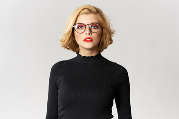 Wall Mural - Blonde girl with glasses red lips black blouse cropped view glamor light background studio