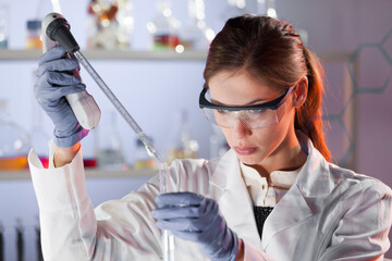 Poster - Life scientists researching in laboratory. Focused female life science professional pipetting solution into the glass cuvette. Lens focus on researcher's eyes. Healthcare and biotechnology concept.