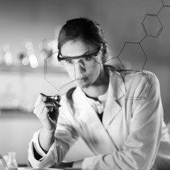 Fototapete - Portrait of a confident female health care expert in life science laboratory writing structural chemical formula on a glass board. Healthcare and modern life science concept. Black and white image.