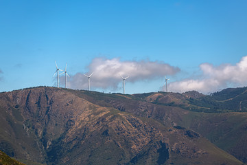 Wall Mural - View of a wind turbines on top of mountains, cloudy sky as background