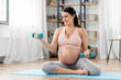 © Syda Productions - pregnancy, sport and fitness concept - happy pregnant woman with light dumbbells exercising at home