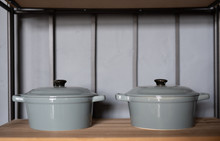 Two Grey Casserole Dishes On A Shelf In A Kitchen
