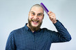 Portrait of crazy bearded bald man holding a comb in his hand. The concept of hair loss and hair transplantation.