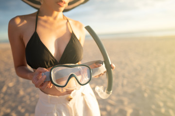 Woman with equipment for snorkeling mask at the beach.