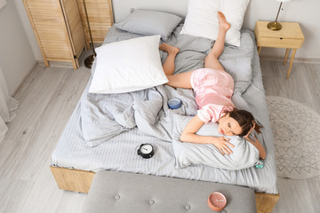 Canvas Print - Young woman with alarm clocks suffering from insomnia in bedroom