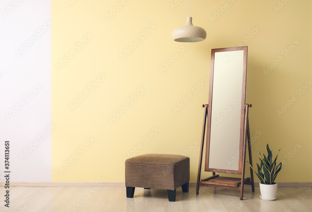 Big mirror with pouf near color wall in room
