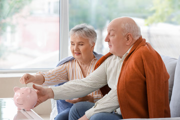 Poster - Senior couple with piggy bank at home