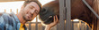 © LIGHTFIELD STUDIOS - horizontal image of farmer looking at camera while touching horse, panoramic shot