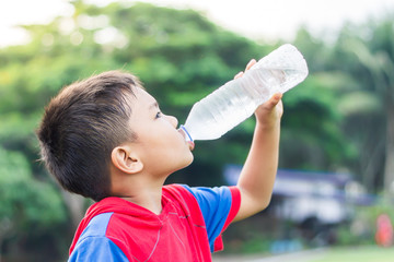 Portrait image of child 5-6 years old. Happy Asian child student boy drinking some water by a plastic bottle. After finished from exercise. Healthy kid and food. Summer season. On white background.