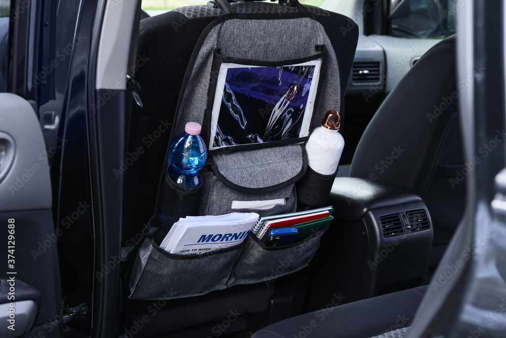 Travel organizer with different things on car seat in salon