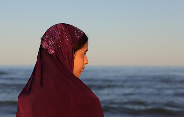 Wall Mural - little girl with look at the seashore with a veil on her head