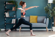 © nenetus - Attractive sporty young woman doing hypopressive exercises in living room at home.