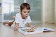 © Yulia Raneva - A boy is reading a book on the floor at home. Image with selective focus