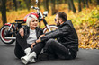 © bedya - Pretty couple near red motorcycle on the road in the forest with colorful blured background
