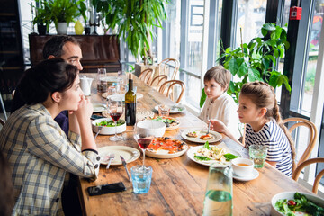 A family of four having a brunch in a cafe on a weekend.