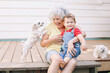 © anoushkatoronto - Grandmother sitting with grandson boy on porch at home backyard. Bonding of relatives and generation communication. Old woman with baby having fun spending time together outdoors.