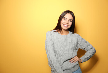 Sticker - Happy young woman wearing warm sweater on yellow background