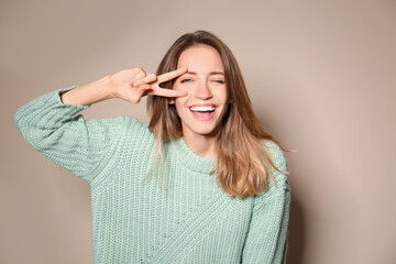 Sticker - Happy young woman wearing warm sweater on beige background