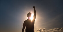 Young strong man with fist up to the sky feeling empowered, and determined. 