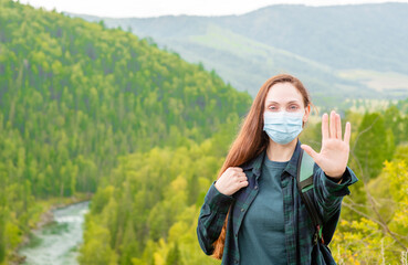 Young woman wearing face mask during coronavirus and flu outbreak showing stop gesture at hike