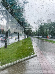 Wall Mural - raindrops water on glass window with blurred city street background