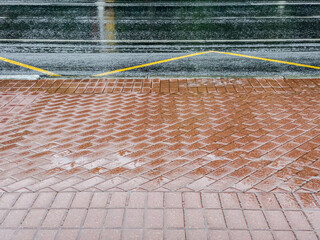 Wall Mural - rainy background with wet red cobblestone pavement and flooded dark asphalt road