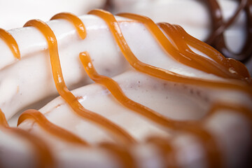 Exquisite creamy cinnamon roll with white coating garnished with caramel.