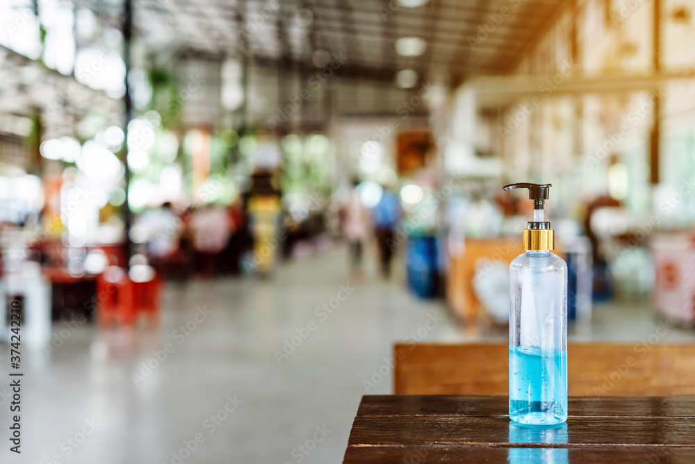 Blue alcohol gel bottle for hand cleaning to prevent the spreading of the Coronavirus (Covid-19) to service for customers placed on table at cafeteria. Healthcare concept. New normal lifestyle - obrazy, fototapety, plakaty 