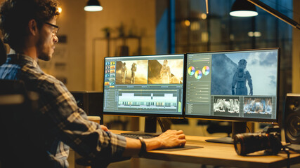 Wall Mural - late evening creative office: professional videographer works on desktop computer, doing footage mon