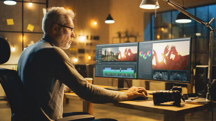 Wall Mural - evening in creative office: professional middle aged videographer works on desktop computer, doing f