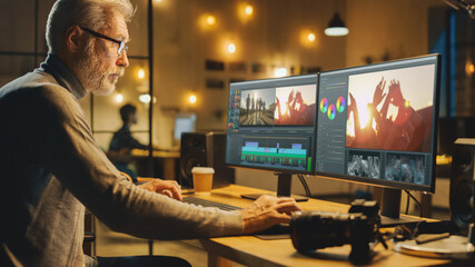 Evening in Creative Office: Professional Middle Aged Videographer Works on Desktop Computer, Doing Footage Montage, Using Video Editing Software. Modern Video Developers Office