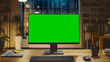 © Gorodenkoff - Desktop Computer with Mock-up Green Screen Standing on the Wooden Desk in the Modern Creative Office. In the Background Warm Evening Lighting and Open Space Studio with City Window View.