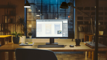 Wall Mural - Shot of a Desktop Computer in the Office Shows Screen with Mobile Phone Application Design, Software UI Development. In the Background Warm Evening Lighting and Open Space Studio with City Window View