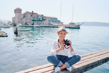 Wall Mural - Tourism concept. Young traveling woman enjoying the view of Kastel Gomilica Castle sitting near the sea on Croatian coast.