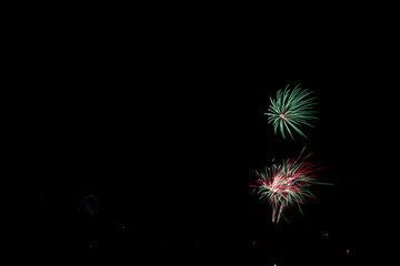 Sticker - Beautiful shot of exploding red green fireworks on a black night sky background