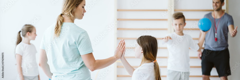 Girl doing high five with her teacher during physical education - obrazy, fototapety, plakaty 