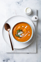 Vegetarian autumn pumpkin and carrot soup with cream, black cumin seeds and green pea micro greens. Fall and winter comfort, healthy slow food